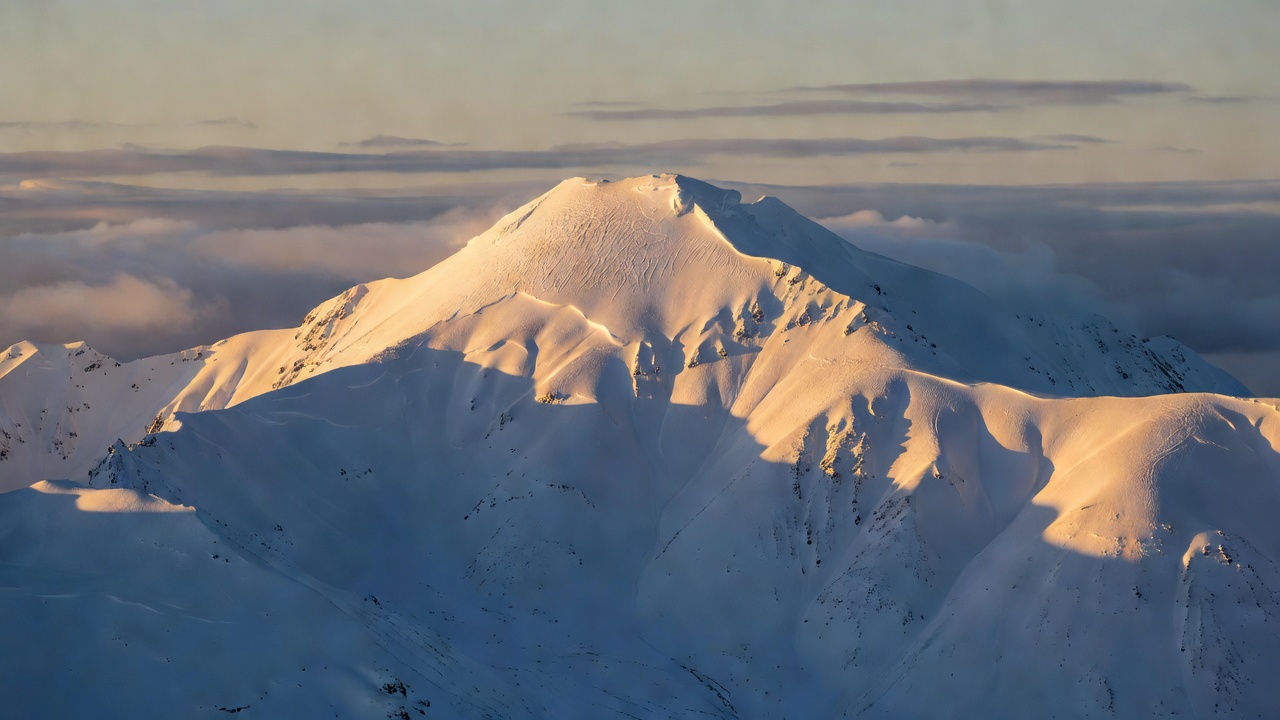清晨日照金山下的雪山主峰与蓝色阴影雪坡，高光保留纹理、暗部保留岩石细节